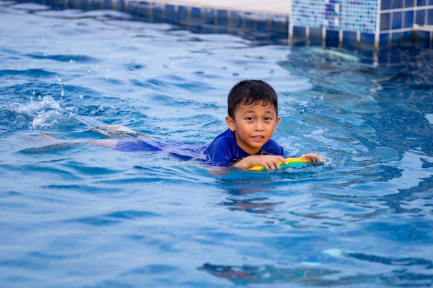 킥보드를 사용하여 수영장에서 수영하는 어린 아이들.