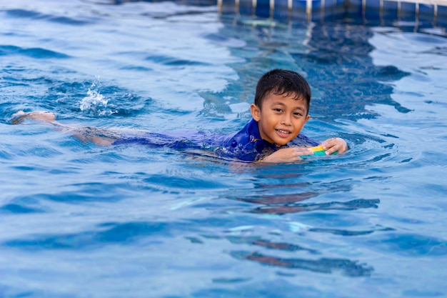 Small children swimming in swimming pool using kick-board.