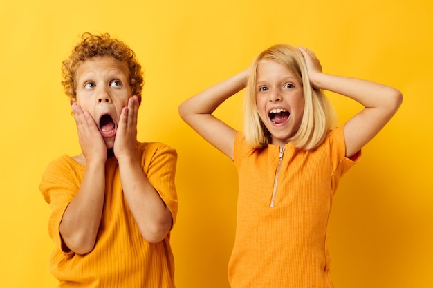 Photo small children in yellow tshirts standing side by side childhood emotions yellow background