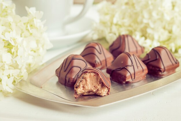 small chocolate candies lie on a plate on a white background