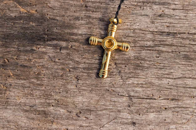 Small Christian golden cross on rustic wooden background Religion concept