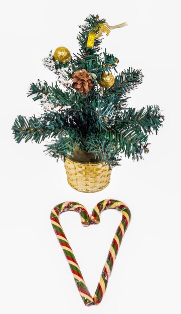 A small Christmas tree and Christmas candies laid out in the shape of a heart.