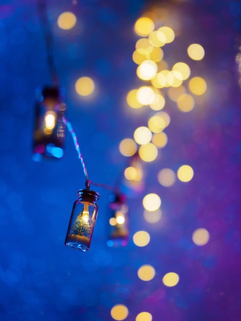 A small Christmas tree in a glass jar Christmas garland Neon bokeh background Vertical photo