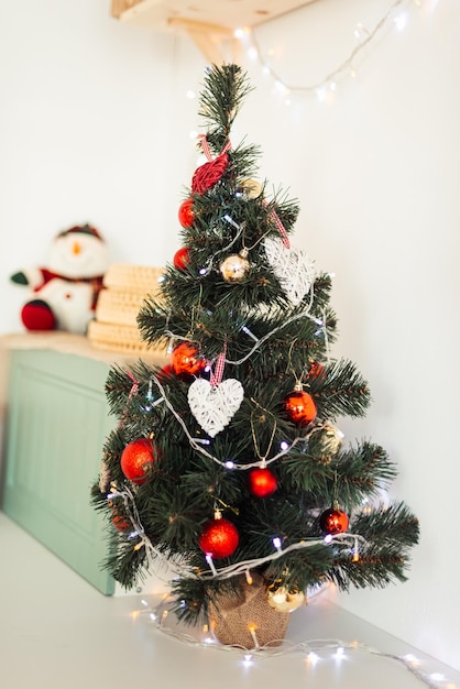 Small Christmas Tree Stands on Table with Red Toys Vertical Card for Merry Christmas