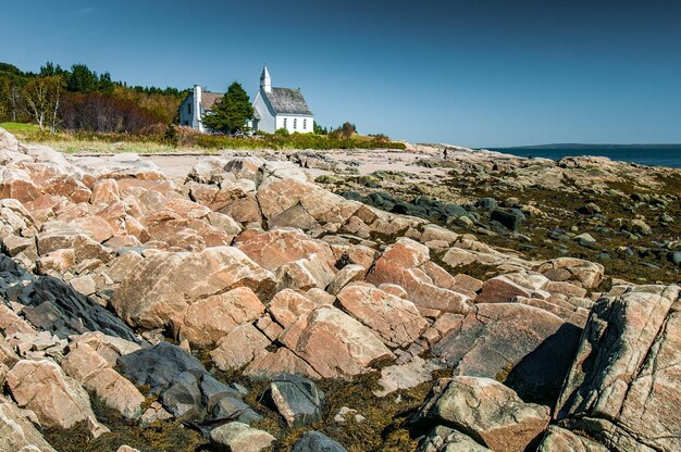 Photo the small church of portaupersil behind the rocks at low tide quebec canada