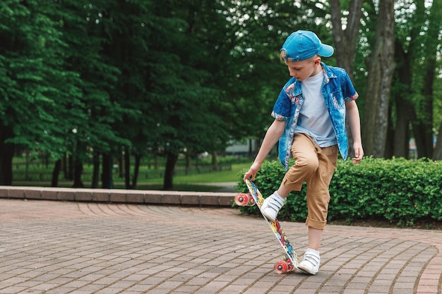 小都市の少年とスケートボード。若い男がパーカースケートボードに乗っています。