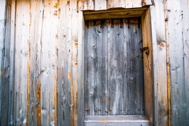 Small closed door in the wooden wall of an old house