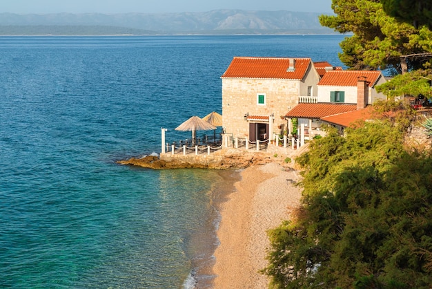 Небольшой прибрежный ресторан на пляже на Адриатическом море в городе Бол, остров Брач, Хорватия, летние каникулы