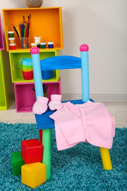 Small and colorful chair with baby clothes