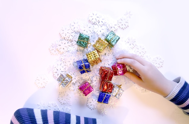 Small colorful gift boxes in child's hands. Christmas and NewYear decorations process.