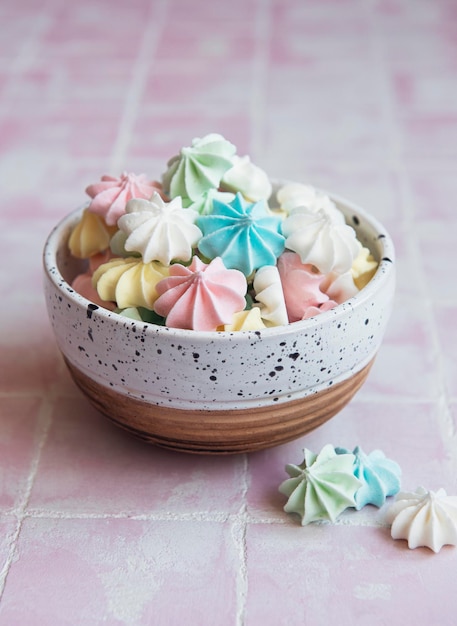 Photo small colorful meringues in the ceramic bowl on tile background