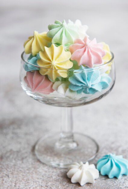 Small colorful meringues in the  glass on concrete background