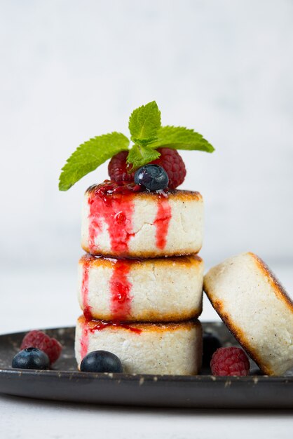 Small cottage cheese pancakes with berries on a white space.