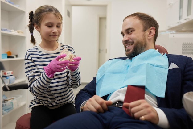 Photo a small curly girl and her father play a dentist happy relationship