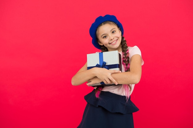 Small cute girl received gift pack with ribbon bow Guess what your child dream about Best toys and christmas gifts Kid little girl in beret hat hold gift box Child excited about unpacking gift