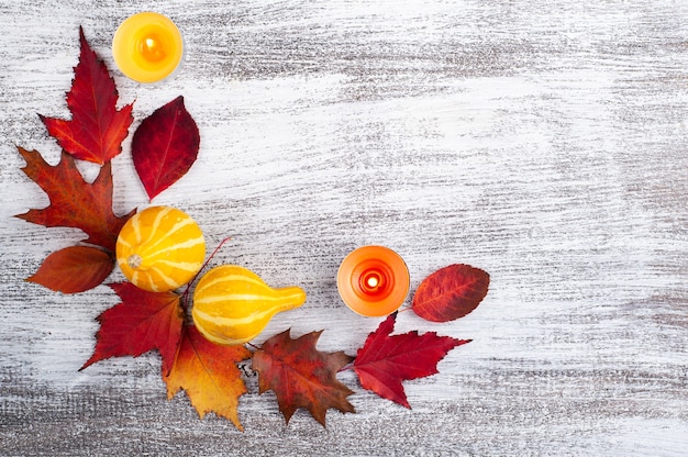 Small decorative pumpkins and falling leaves wreath on rustic wooden table