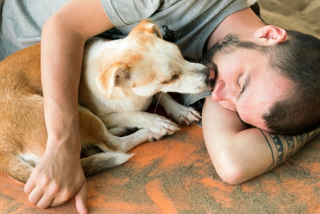 Foto piccolo cane che lecca il viso dell'uomo