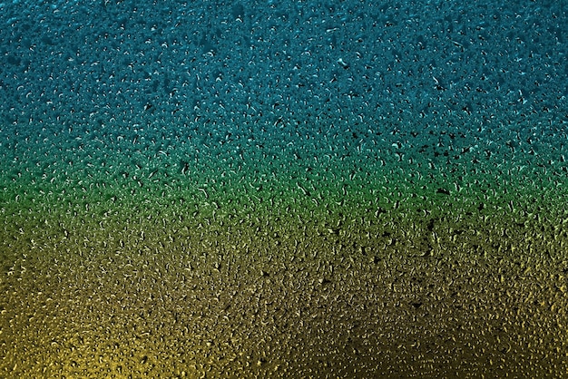 Small drops of water or condensate on the metal surface are yellow and blue Abstract background for a screen saver