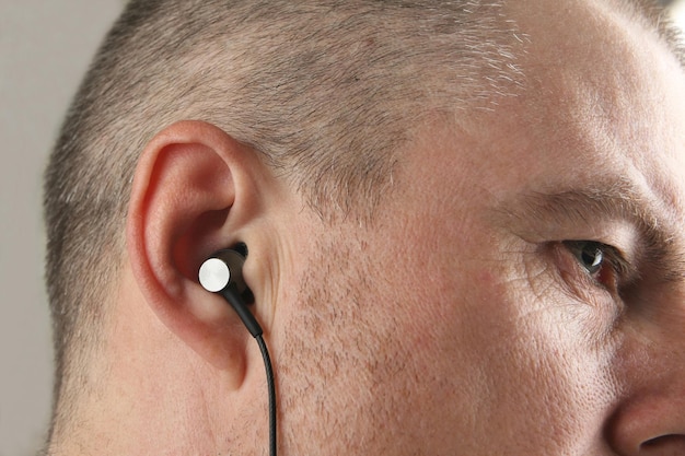 Small earphones inserted into the ear of men close up