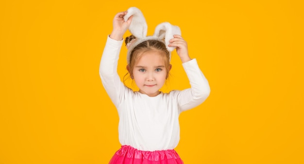 Small easter child in bunny ears on yellow background