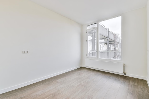 Small empty room with a parquet floor and a large window in a cozy house