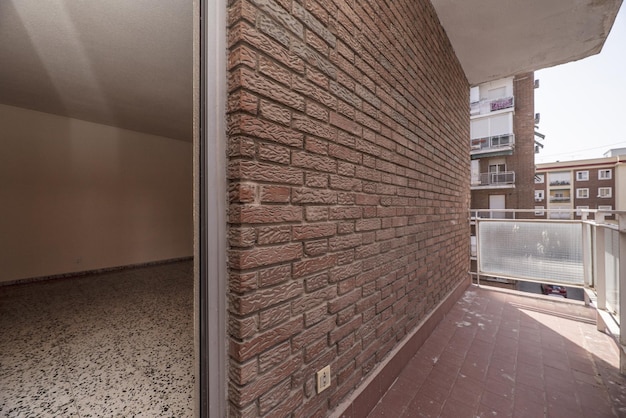 Small empty terrace with exposed brick clay floors and metal railing and translucent glass