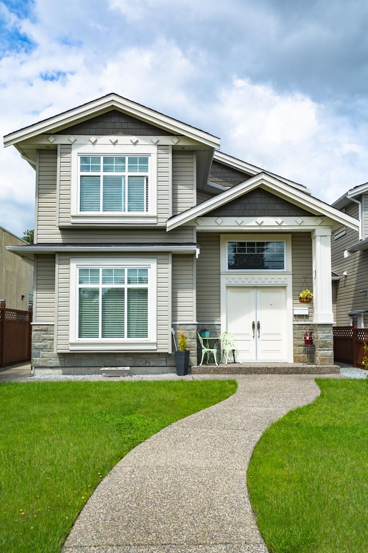 Small family house with curved concrete pathway over green lawn over front yard