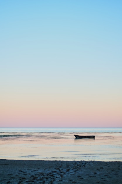 Small fishing boat in bay at dusk sunset