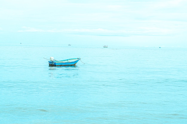 Small fishing boat floating in blue sea with blue sky