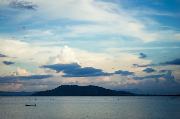 Small fishing boat in the lake with background sunrise or sunset clouds sky.