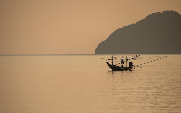 Un piccolo peschereccio ormeggiato in mezzo al mare durante il tramonto