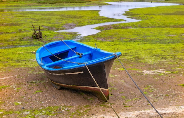 Small fishing boat moored in the mudflat at low tide