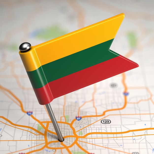 Photo small flag of lithuania sticked in the map background with selective focus.