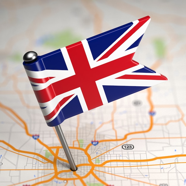 Photo small flag of united kingdom of great britain on a map background with selective focus.