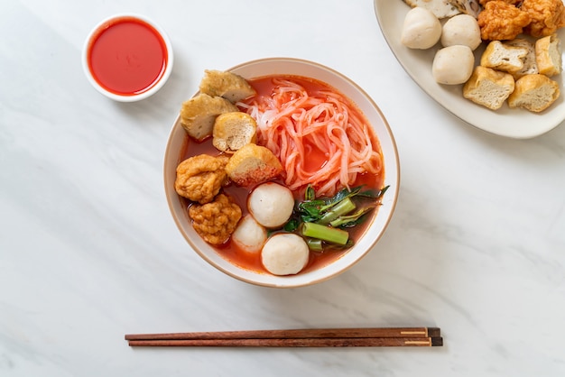 Small flat rice noodles with fish balls and shrimp balls in pink soup