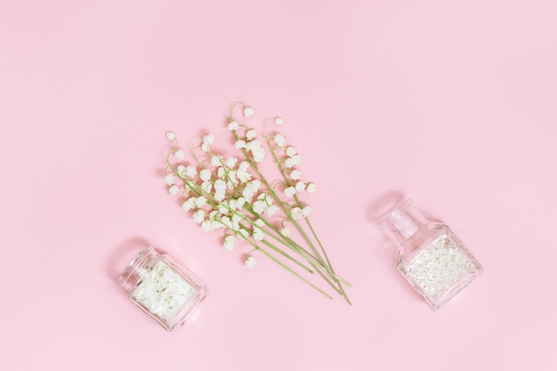 Small flowers of lilies of the valley and glass bottle with dry petals