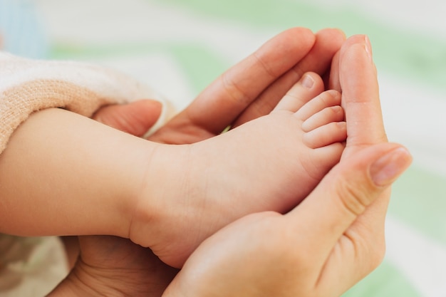 Small foot of a newborn baby in the hands of an adult.