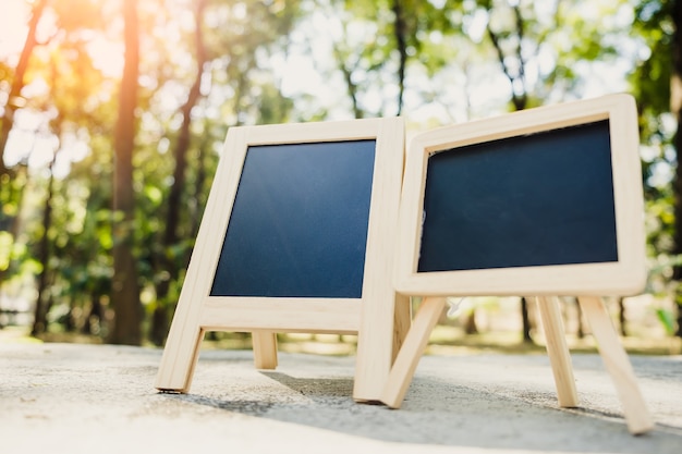 Small A-frame blackboard with blank area for text or message on rustic wood table in morning time