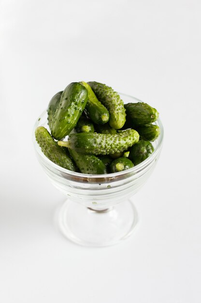 Photo small fresh clean green cucumbers in a crystal glass on a white background