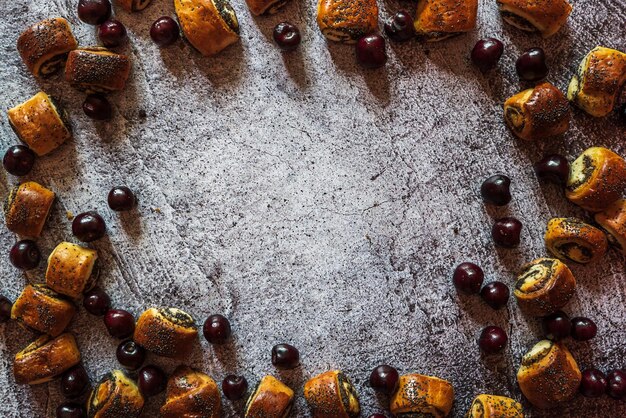 Small fresh homemade buns with poppy seeds and cherries on a gray table background for text 1