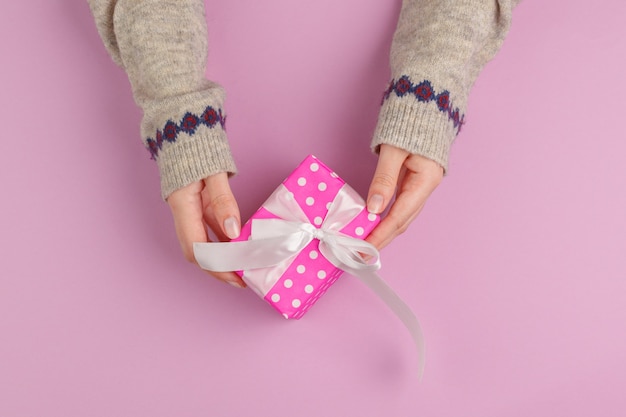 Small gift box in female hands view from above