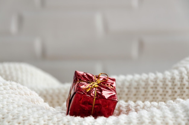 A small gift on a knitted white plaid Red packaging Gift wrap Gift box