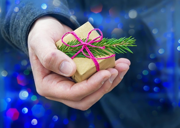 A small gift in a man's hand on the bokeh background, selective focus.