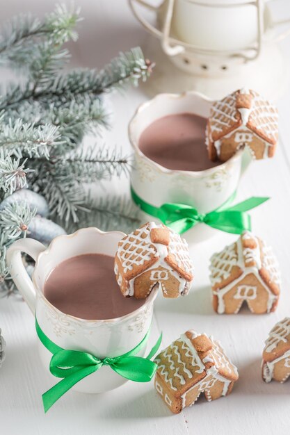 Small gingerbread cottages with sweet drink in Christmas winter evening