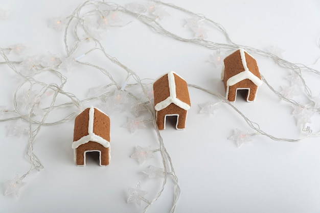 Small gingerbread houses on white background and christmas garlands. Christmas baked goods.