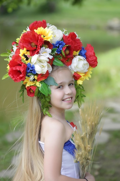 Small girl in embriodered dress and flower national wreath