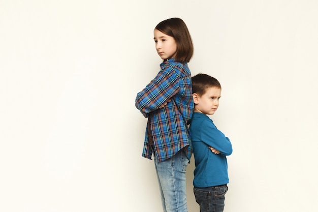 Маленькая девочка и ее брат стоят спиной к спине