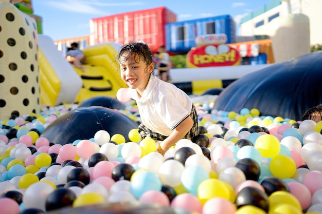 写真 夏休みに弾むボールハウスで遊ぶ制服を着た小さな女の子