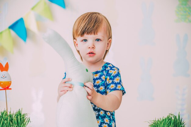 Small girl is playing with easter toy rabbit with grass