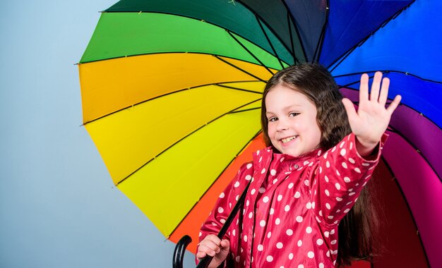 Small girl in raincoat. autumn fashion. cheerful hipster child in positive mood. rain protection. Rainbow. happy small girl with colorful umbrella. Casually beautiful.